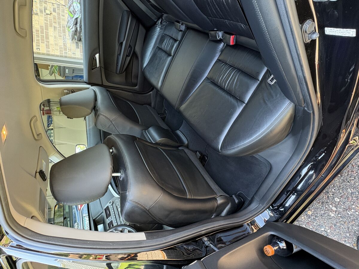 Freshly detailed black leather car interior with the door open in a driveway