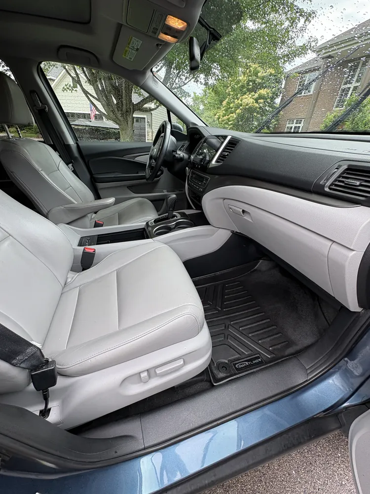 Cleaned SUV interior with detailed light-gray leather seats, dash and floor mats