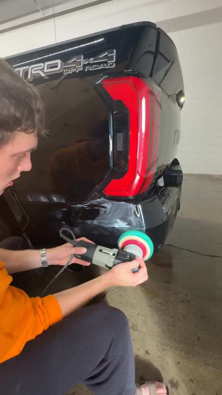 A GrandVista detailer machine-polishing the rear of a black Toyota Tundra